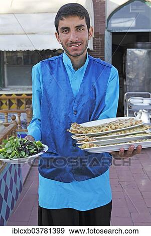 Stock Photo - "Waiter serving bread and salad in a traditional restaurant, Bazaar, Isfahan, Isfahan Province, Persia, Iran, Asia". Fotosearch