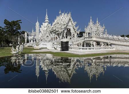 Stock Image - "Wat Rong Khun, White Temple, by architect Chalermchai Kositpipat, ubosot reflected in the water, Chiang Rai, Chiang Rai Province, Northern Thailand, Thailand, Asia". Fotosearch