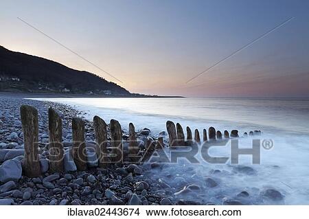 "Waves washing over rocks, split by a groyne, at dusk, with the village of Porlock Weir at back, England, United Kingdom, Europe" View Large Photo Image Picture - "Waves washing over rocks, split by a groyne, at dusk, with the village of Porlock Weir at back, England, United Kingdom, Europe". Fotosearch