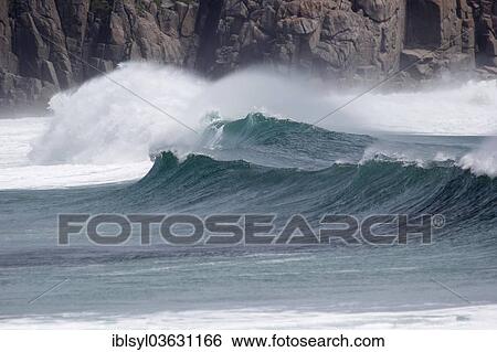 Stock Photograph - "Waves with spray in front of a cliff, Porthcurno, St Levan, Cornwall, England, United Kingdom, Europe". Fotosearch