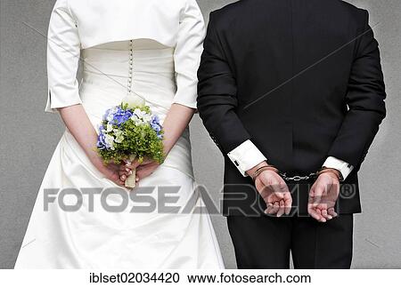 "Wedding couple seen from behind, the bride is holding a bridal bouquet, the groom is wearing handcuffs" View Large Photo Image Stock Image - "Wedding couple seen from behind, the bride is holding a bridal bouquet, the groom is wearing handcuffs". Fotosearch