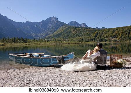Stock Image - "Wedding couple with a boat at Almsee Lake, Totes Gebirge, Dead Mountains, Salzkammergut, Upper Austria, Austria, Europe". Fotosearch