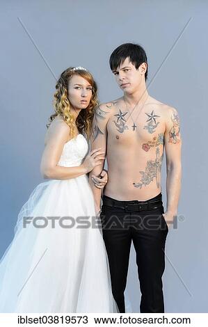 Stock Image - "Wedding picture, bride and groom, bare chested groom with tattoos". Fotosearch