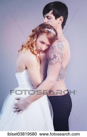 Stock Image - "Wedding picture, bride and groom, bare chested groom with tattoos". Fotosearch