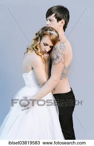 Stock Image - "Wedding picture, bride and groom, bare chested groom with tattoos". Fotosearch