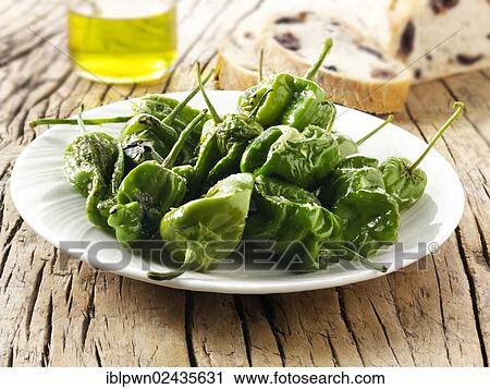 Stock Image - Whole griddled Padron peppers snack with sea salt. Fotosearch