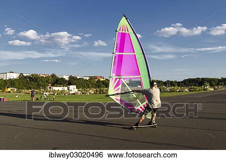 Stock Photograph - "Windskater practicing on the asphalt runway with a windsurfer sail and a longboard, Berlin-Tempelhof, Tempelhofer Feld, Berlin, Berlin, Germany, Europe". Fotosearch