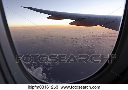 Wing of a high flying Boeing 777 long reach aircraft seen through passenger window at sunset View Large Photo Image Stock Image - Wing of a high flying Boeing 777 long reach aircraft seen through passenger window at sunset. Fotosearch