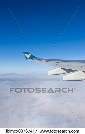 "Wing of an Oman Air airplane above the clouds, Germany, Europe" View Large Photo Image Stock Photo - "Wing of an Oman Air airplane above the clouds, Germany, Europe". Fotosearch