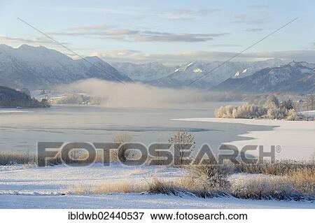 Stock Photo - "Winter landscape, Lake Riegsee in front of Estergebirge mountains, Wetterstein range and Ammergau Alps with Ettaler Mandl peak, Murnau, Pfaffenwinkel region, Upper Bavaria, Germany, Europe". Fotosearch