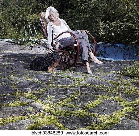 "Woman, 65-75 years, sitting in an overgrown garden in a rocking chair, stroking her dog, Innsbruck, Tyrol, Austria, Europe" View Large Photo Image Stock Photo - "Woman, 65-75 years, sitting in an overgrown garden in a rocking chair, stroking her dog, Innsbruck, Tyrol, Austria, Europe". Fotosearch