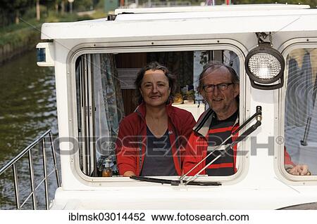 "Woman and man at the wheel of a Penichette, a houseboat on the Canal des Vosges, formerly Canal de l'Est, Selles, Vesoul, Region Franche-Comte, Dep. Haute-Saone, France, Europe" View Large Photo Image Stock Image - "Woman and man at the wheel of a Penichette, a houseboat on the Canal des Vosges, formerly Canal de l'Est, Selles, Vesoul, Region Franche-Comte, Dep. Haute-Saone, France, Europe". Fotosearch