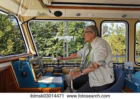 "Woman at the wheel of a Penichette, a houseboat on the Canal des Vosges, formerly Canal de l'Est, Thaon-les-Vosges, Epinal, Lorraine, Departement Vosges, France, Europe" View Large Photo Image Stock Image - "Woman at the wheel of a Penichette, a houseboat on the Canal des Vosges, formerly Canal de l'Est, Thaon-les-Vosges, Epinal, Lorraine, Departement Vosges, France, Europe". Fotosearch