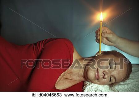 Stock Image - Woman being treated with an ear candle. Fotosearch