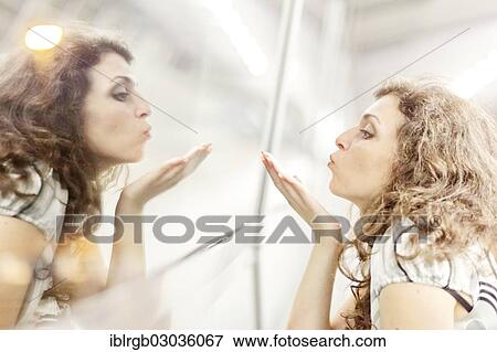 Stock Photo - "Woman blowing a kiss to her mirror image, Allgaeu, Kempten, Allgau, Swabia, Bavaria, Germany, Europe". Fotosearch