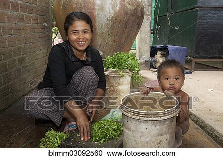 Stock Image - "Woman cutting herbs, Siem Reap, Siem Reap, Siem Reap Province, Cambodia, Asia". Fotosearch