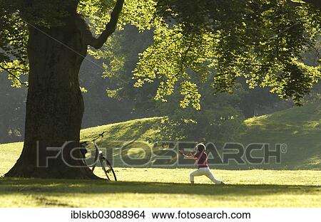 "Woman doing yoga exercises in the park in the morning sun, Englischer Garten, Munich, Upper Bavaria, Bavaria, Germany, Europe" View Large Photo Image Picture - "Woman doing yoga exercises in the park in the morning sun, Englischer Garten, Munich, Upper Bavaria, Bavaria, Germany, Europe". Fotosearch