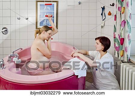 Stock Photo - "Woman during childbirth in a birthing bath in the maternity delivery room beside her midwife, Germany, Europe". Fotosearch