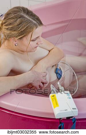 Stock Photography - "Woman during childbirth with a cardiotocography or CTG in a birthing bath in the maternity delivery room, Germany, Europe". Fotosearch