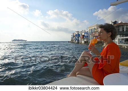 Picture - "Woman enjoying a cocktail and a view over the sea, Little Venice, Mykonos Town, Mykonos, Cyclades, Greece, Europe". Fotosearch
