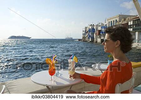 "Woman enjoying a cocktail and a view over the sea, Little Venice, Mykonos Town, Mykonos, Cyclades, Greece, Europe" View Large Photo Image Stock Photo - "Woman enjoying a cocktail and a view over the sea, Little Venice, Mykonos Town, Mykonos, Cyclades, Greece, Europe". Fotosearch