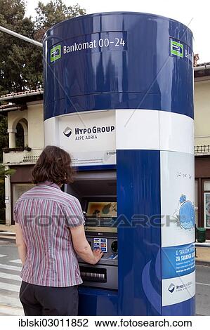 Stock Image - "Woman extracting money from an ATM of the bank of Hypo Group Alpe Adria in Opatija, Istria, Croatia, Europe, Opatija, Croatia, Europe". Fotosearch