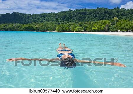 Stock Image - "Woman floating in the water off Champagne Beach, Espiritu Santo, Sanma Province, Vanuatu, Oceania". Fotosearch