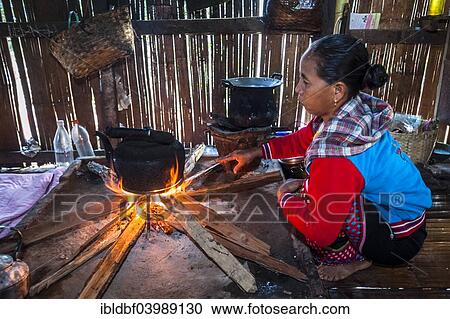 Stock Image - "Woman from the Lahu people, hill tribe, ethnic minority, cooking on an open fire in a kitchen made of bamboo, Mae Hong Son Province, Northern Thailand, Thailand, Asia". Fotosearch