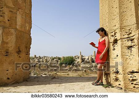 Stock Image - "Woman holding a book leaning against a column of Temple E, Temple of Hera, Selinunt, Trabant, Sizilien, Italy, Europe". Fotosearch