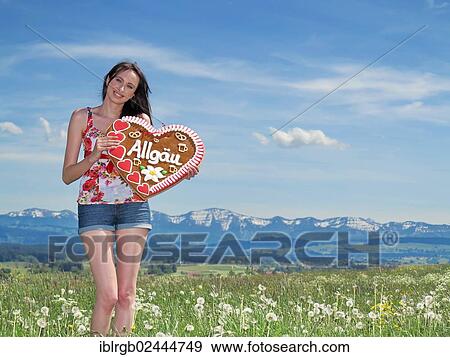 Woman holding a gingerbread heart labelled with the word Allgaeu View Large Photo Image Stock Photo - Woman holding a gingerbread heart labelled with the word Allgaeu. Fotosearch