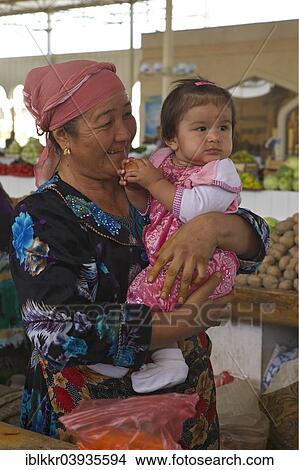 Picture - "Woman holding a little girl in her arms, at a bazaar, Bukhara, Uzbekistan, Asia". Fotosearch