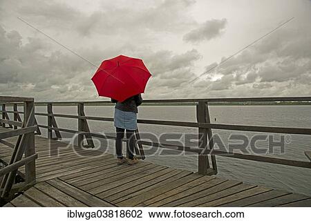 "Woman holding a red umbrella on a wharf on Federsee lake, Upper Swabia, Baden-Wurttemberg, Germany, Europe" View Large Photo Image Stock Image - "Woman holding a red umbrella on a wharf on Federsee lake, Upper Swabia, Baden-Wurttemberg, Germany, Europe". Fotosearch