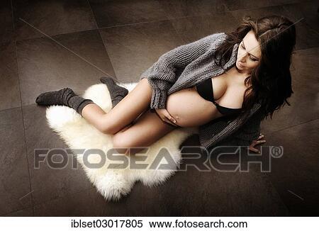 "Woman holding her pregnant belly, in underwear, socks and a cardigan, sitting on the floor" View Large Photo Image Stock Photography - "Woman holding her pregnant belly, in underwear, socks and a cardigan, sitting on the floor". Fotosearch