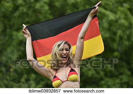 "Woman in a bikini in the German national colours holding the national flag of Germany, cheering" View Large Photo Image Stock Photo - "Woman in a bikini in the German national colours holding the national flag of Germany, cheering". Fotosearch