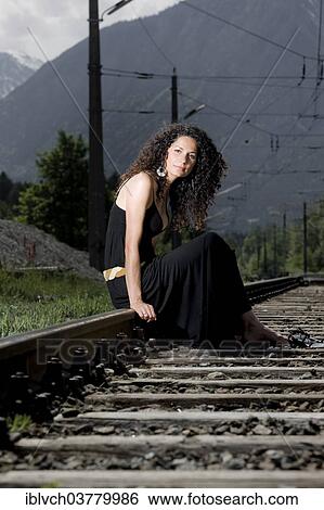 "Woman in a dress sitting on railroad tracks, Tyrol, Austria, Europe" View Large Photo Image Stock Photograph - "Woman in a dress sitting on railroad tracks, Tyrol, Austria, Europe". Fotosearch
