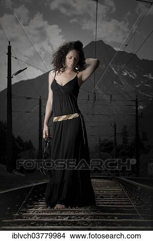 Picture - "Woman in a dress walking on railroad tracks, Tyrol, Austria, Europe". Fotosearch