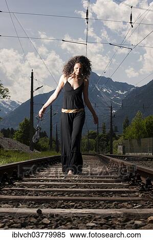 Stock Photography - "Woman in a dress walking on railroad tracks, Tyrol, Austria, Europe". Fotosearch