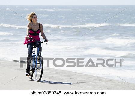 "Woman in a summer dress riding a bicycle by the sea, Norderney, Lower Saxony, Germany, Europe" View Large Photo Image Stock Photography - "Woman in a summer dress riding a bicycle by the sea, Norderney, Lower Saxony, Germany, Europe". Fotosearch