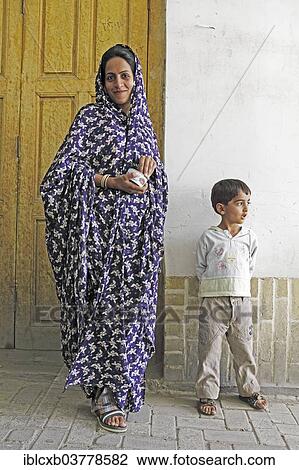 Stock Image - "Woman in modern chador with son, old town, Yazd, Yazd Province, Persia, Iran, Asia". Fotosearch