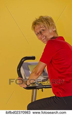 "Woman in the gym, sitting on a bike, smiling" View Large Photo Image Stock Image - "Woman in the gym, sitting on a bike, smiling". Fotosearch