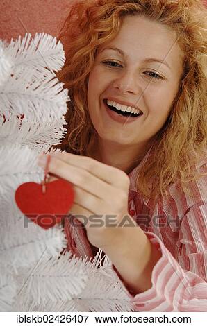 Stock Photo - Woman is decorating a white Christmas tree. Fotosearch
