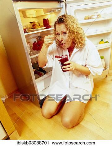 Woman kneeling in front of an open refrigerator in a nightshirt and eating red jelly View Large Photo Image Stock Image - Woman kneeling in front of an open refrigerator in a nightshirt and eating red jelly. Fotosearch
