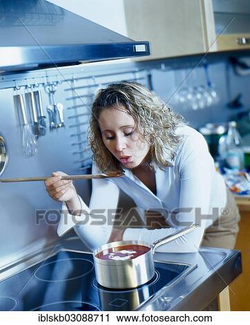 Woman leaning on the stove and tasting tomato soup with a spoon View Large Photo Image Stock Image - Woman leaning on the stove and tasting tomato soup with a spoon. Fotosearch