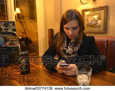 "Woman looking at her smartphone in a pub, Leeds, West Yorkshire, England, United Kingdom, Europe" View Large Photo Image Stock Photo - "Woman looking at her smartphone in a pub, Leeds, West Yorkshire, England, United Kingdom, Europe". Fotosearch