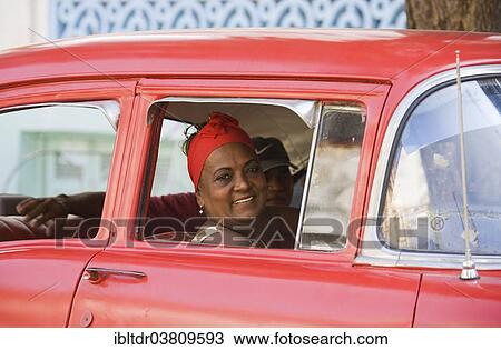 Stock Image - "Woman looking out of a car window, classic car, Havana, Cuba, North America". Fotosearch