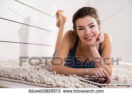 Stock Image - Woman lying on the floor with a tablet computer. Fotosearch