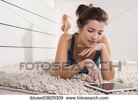 Woman lying on the floor with a tablet computer View Large Photo Image Stock Photo - Woman lying on the floor with a tablet computer. Fotosearch