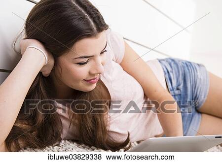 Woman lying on the floor with a tablet computer View Large Photo Image Stock Photo - Woman lying on the floor with a tablet computer. Fotosearch