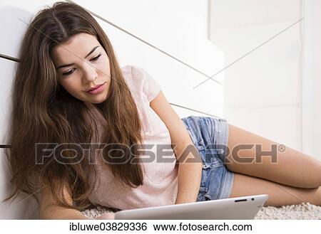 Woman lying on the floor with a tablet computer View Large Photo Image Stock Photograph - Woman lying on the floor with a tablet computer. Fotosearch