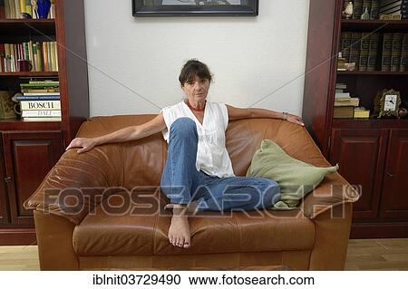 "Woman, mid 60s, sitting on a sofa" View Large Photo Image Stock Image - "Woman, mid 60s, sitting on a sofa". Fotosearch